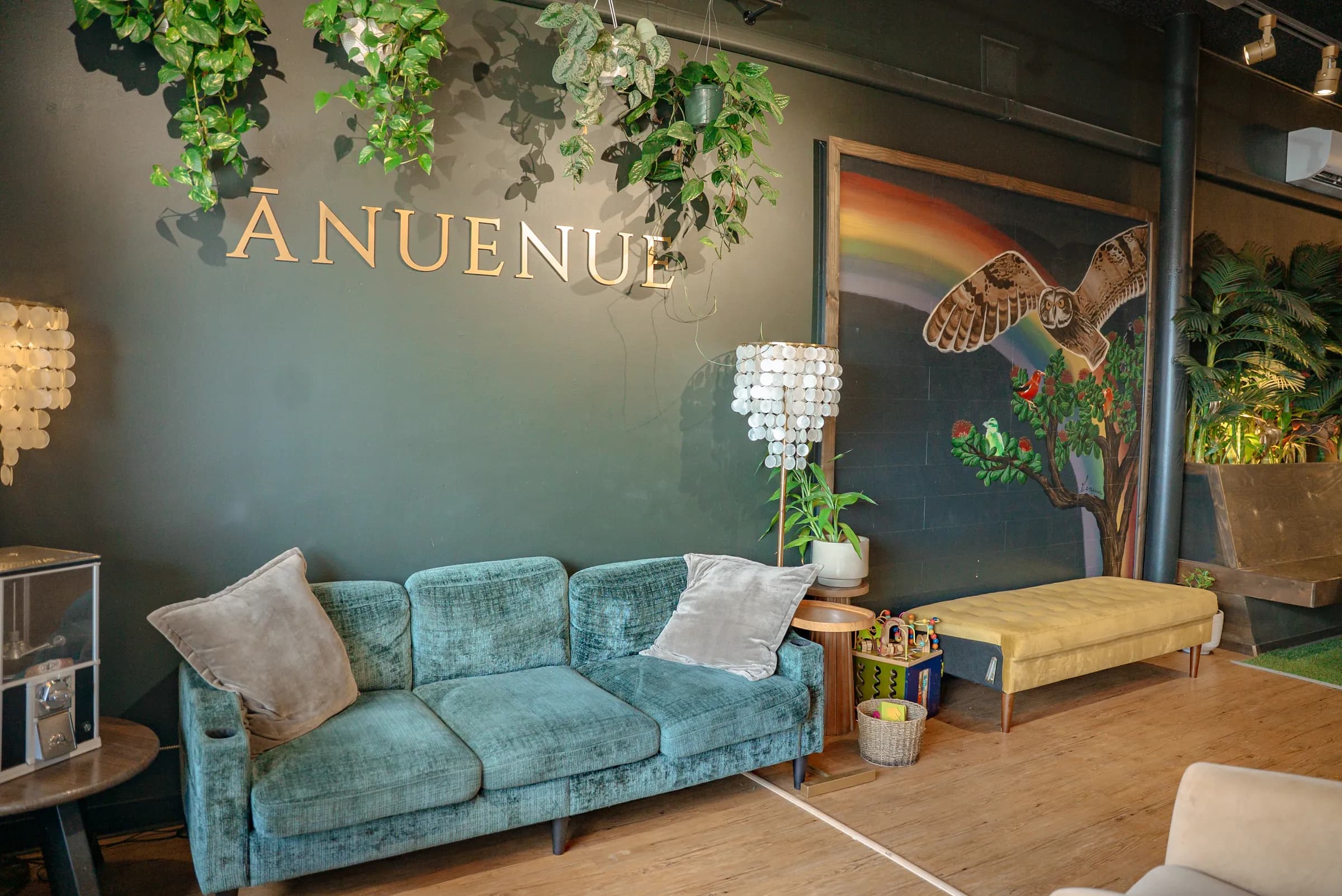 The lounge set up warmly under the brass lettering and the painted rainbow mural